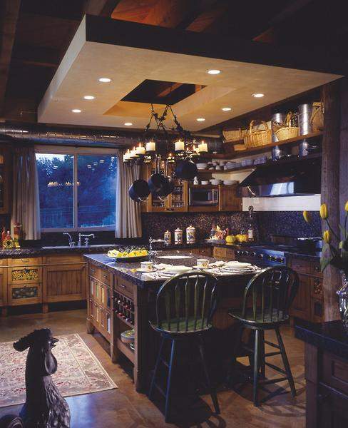 In the kitchen, a “floating plane” adds a dramatic, contemporary flourish to 
the room. The center hole allows a combination pot rack/chandelier plenty of room to hang over the island. The plane, Landry says, also “softens the rhythm made by the ceiling beams—which are actually the joists supporting the floor above.”
