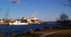 Portsmouth Naval Shipyard Point, Old Navy Prison, and Coast Guard Cutter at dock- from shore of Portsmouth New Hampshire.  The big white building in the back is the old Navy Prison - WWII prisoners were held here.