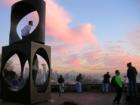 Queen Anne's Kerry Park at dusk with Space Needle, Mt Rainier, Sculpture (and guy sitting inside) and visitors enjoying the view