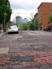 Brick streets can be found in the River Market area of Kansas City.  Outside of many lofts for sale is this street with it's view of downtown.