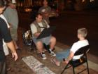 Street artist draws a tourist as onlookers watch his work.