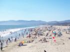 Crowded beach on a sunny day by the Santa Monica Pier with a view to the north to Malibu