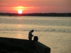 Fisherman baiting a line with the sunset sinking into the Intracoastal Waterway