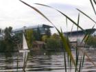 University of Washington's Husky Stadium seen from Montlake's Waterfront Park with a Sailboat about to enter the Montlake Cut to go to Lake Union.