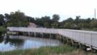 Port Orange park with walking path and bridges over and around a small lake with fountain.