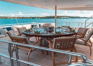 The teak dining table on the bridge deck is set for eight this time