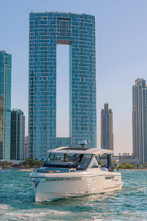 Front view of Saxdor 400 GTO ICE yacht cruising in Dubai waters with city skyline in background.