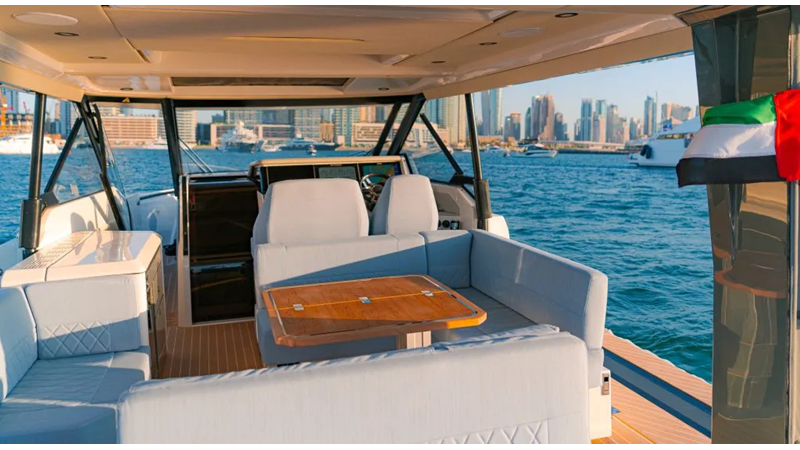 Saxdor 400 GTO ICE cockpit lounge with wraparound seating, wooden dining table, and panoramic Dubai Marina skyline views.