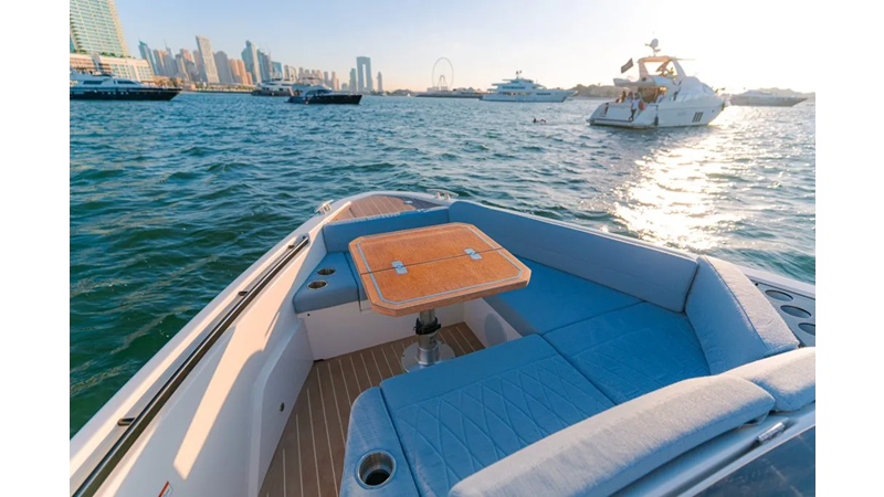 Saxdor 400 GTO ICE Bow seating area with teak table on a luxury yacht, overlooking the ocean and nearby yachts in the harbor.
