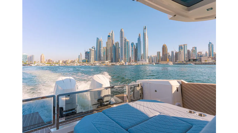 Saxdor 400 GTO ICE Luxury yacht cruising with rear sunpad seating, ocean wake, and city skyline in the background