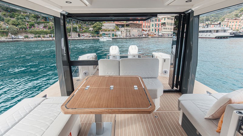 Saxdor 400 GTO ICE cockpit lounge with wraparound seating, wooden dining table, and panoramic Dubai Marina skyline views.