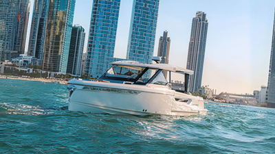 Front view of Saxdor 400 GTO ICE yacht cruising in Dubai waters with city skyline in background.