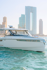 Front view of Saxdor 400 GTO ICE yacht cruising in Dubai waters with city skyline in background.