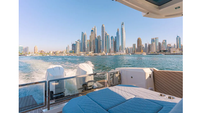 Saxdor 400 GTO ICE Luxury yacht cruising with rear sunpad seating, ocean wake, and city skyline in the background