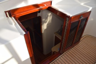 Locking entry door to cabin, teak and glass folding door with keeper and slide back solid top panel.