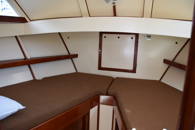 Shelves and reading lights in V-berth, trimmed with teak in Herreshoff styling