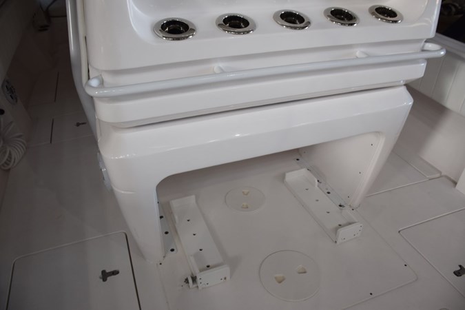 Behind helm seat console, drink holder or rod holders and safety grab railing, cooler chocks beneath.