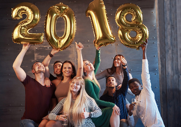 A group of merry young people hold numbers indicating the arrival of a new 2018 year. The party is dedicated to the celebration of the new year. Concepts about youth togetherness lifestyle.