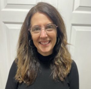 A woman smiling in front of a plain background.