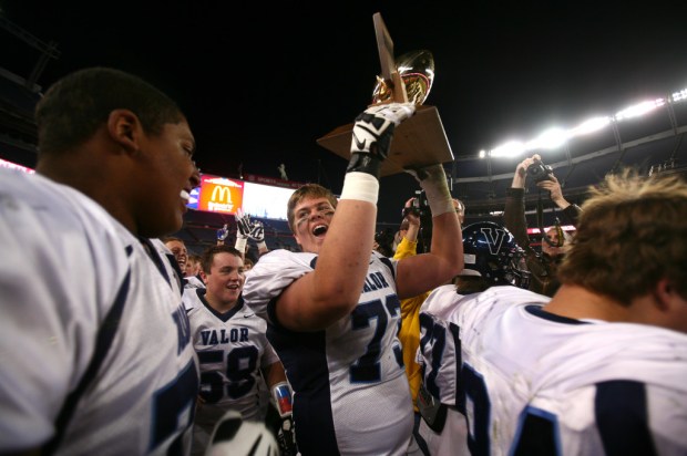 Valor senior offensive and defensive lineman Ryan Cummings (73) raises the championship while celebrating his team's CHSAA 5A state championship win over Fairview, Saturday, Nov. 30, 2013, at Sports Authority Field at Mile High Stadium. (Kai Casey/CHSAANow.com)