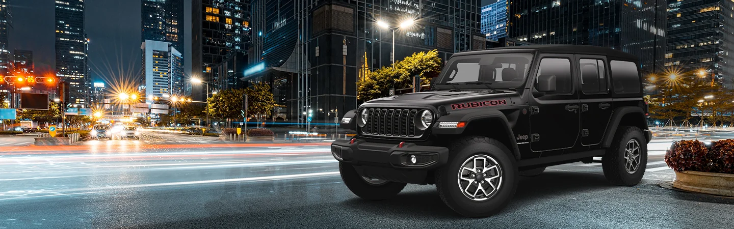 Front side view of a black 2026 Jeep Wrangler parked on a city street