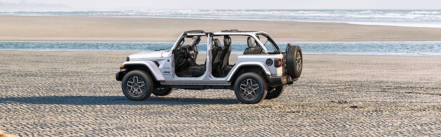Side view of a parked white 2026 Jeep Wrangler parked on a beach
