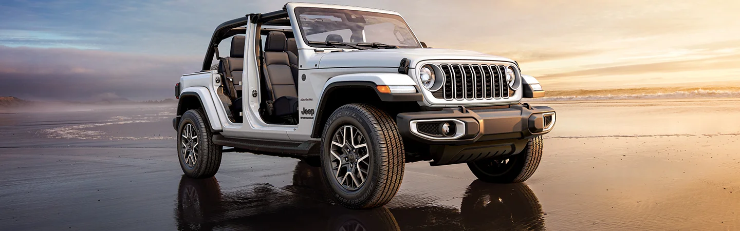Front side view of a white 2026 Jeep Wrangler parked on a beach