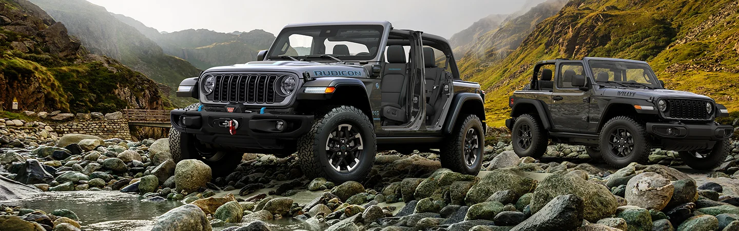 Two 2026 Jeep Wrangler parked on a rocky river bank