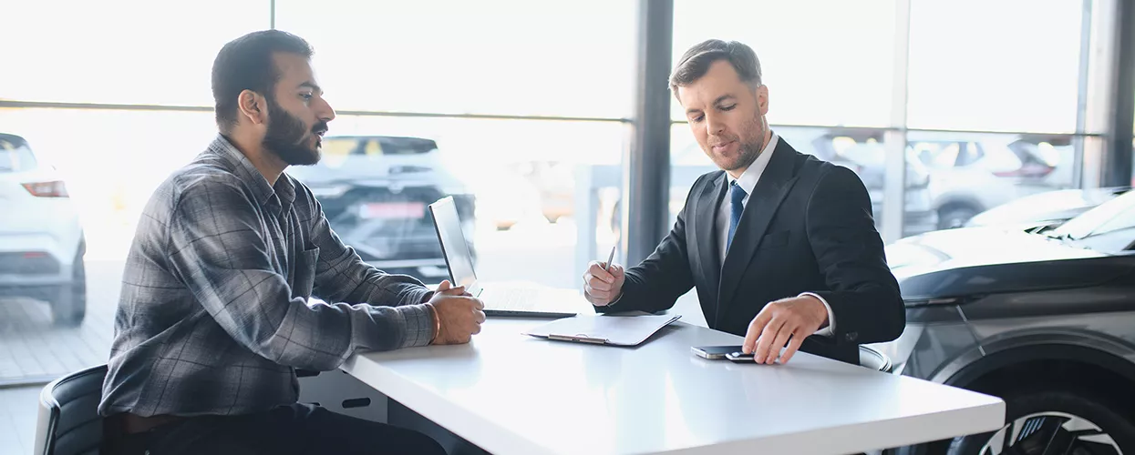 Car salesman walking a customer through a contract at a Jaguar dealership