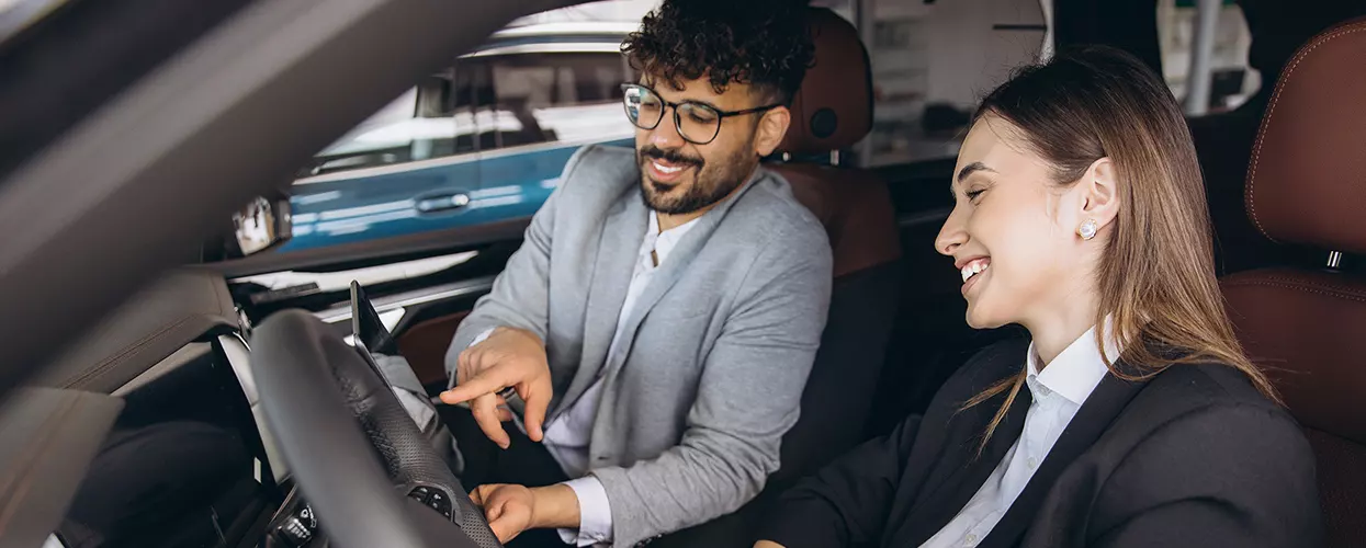 Car salesman and customer sitting in a vehicle at a car dealership