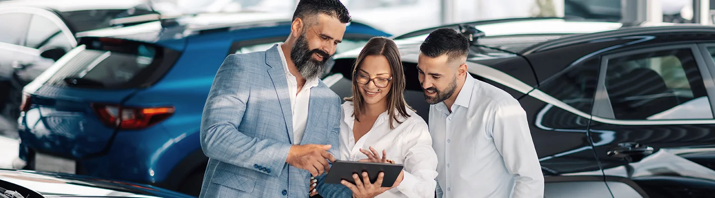 A Couple speaking with Salesperson looking at digital tablet with car purchasing information on screen in Nederland TX