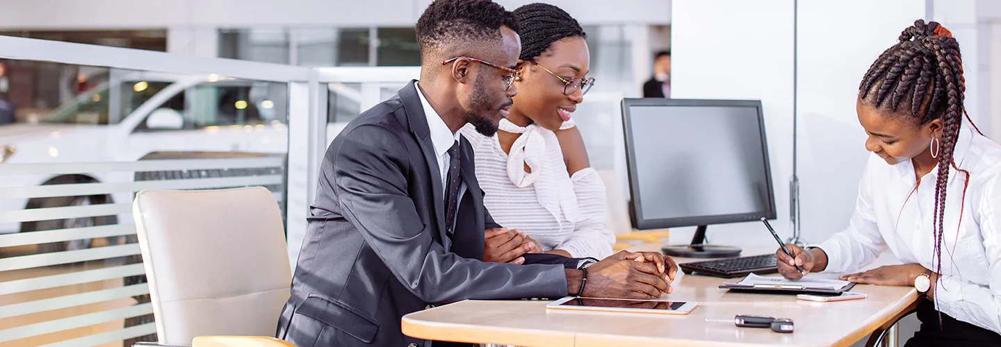 couple speaqking with car salesperson in dealership