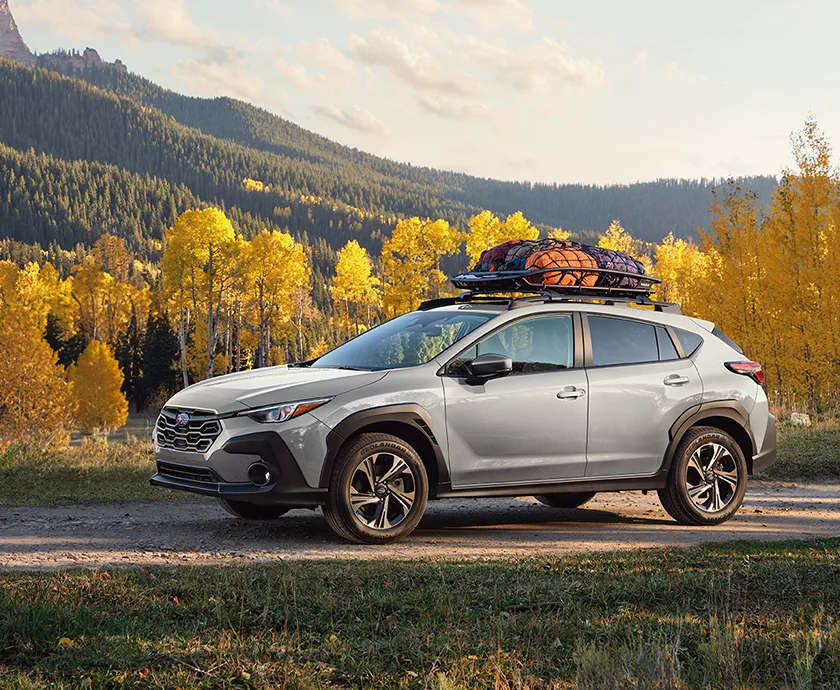 Side view of a parked gray 2026 Subaru Crosstrek on a dirt road in the forest getting ready for camping