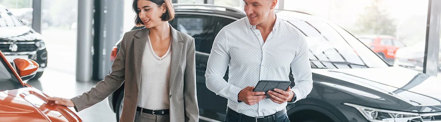 two people discussing car purchase in shwrooom with one holding a digital tablet in Nederland, TX