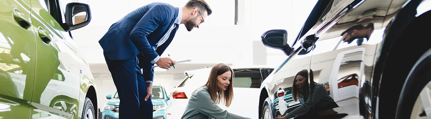 person in suit speaking with person checking tires on car on showroom at Colonial Volkswagen