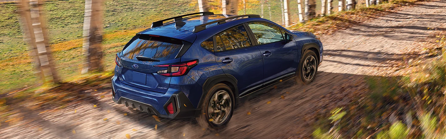 A blue 2025 Subaru Crosstrek driving the woods