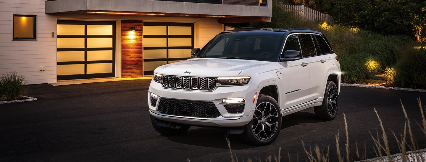 White 2025 Jeep Grand Cherokee parked in front of a house
