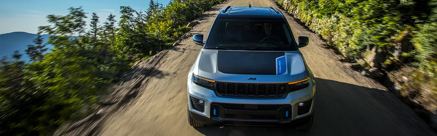 Front view of a 2025 Jeep Grand Cherokee driving on a dirt road
