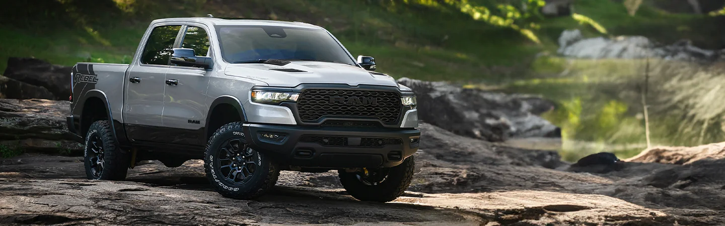 Front side view of a gray 2026 RAM 1500 parked on some rocks