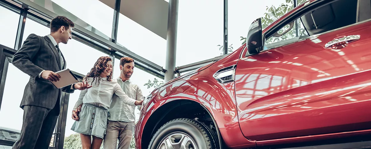 Car salesman showing a couple a new vehicle