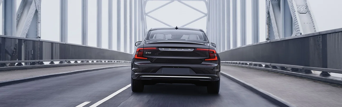 Back view of a 2025 Volvo S90 Hybrid driving on a bridge