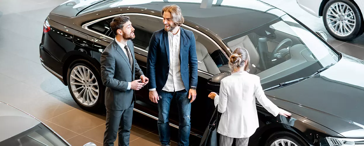 Car salesman showing a couple a new vehicle at a Genesis dealership