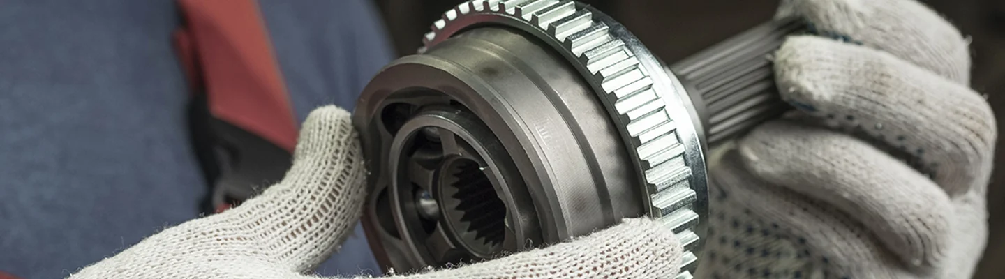 hands of a auto mechanic holding a gear part to transmission