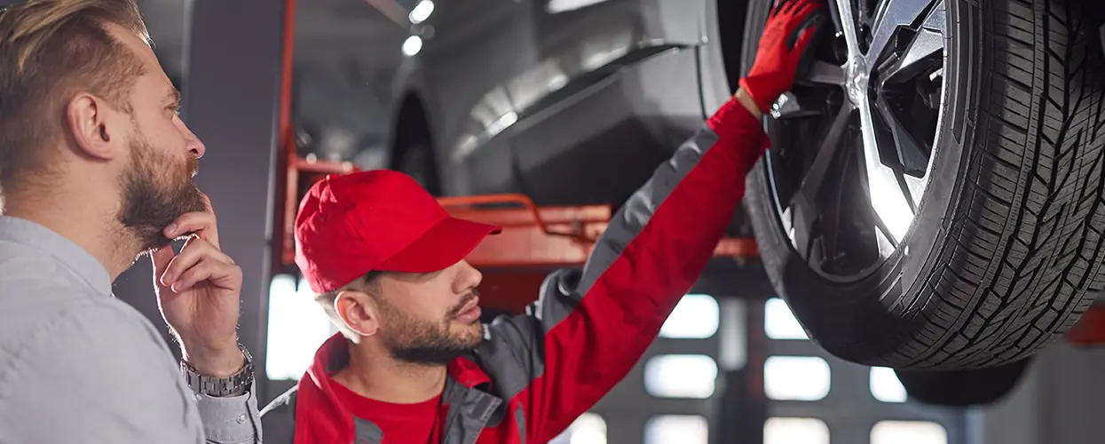 Rep showing a customer a wheel of car on lift