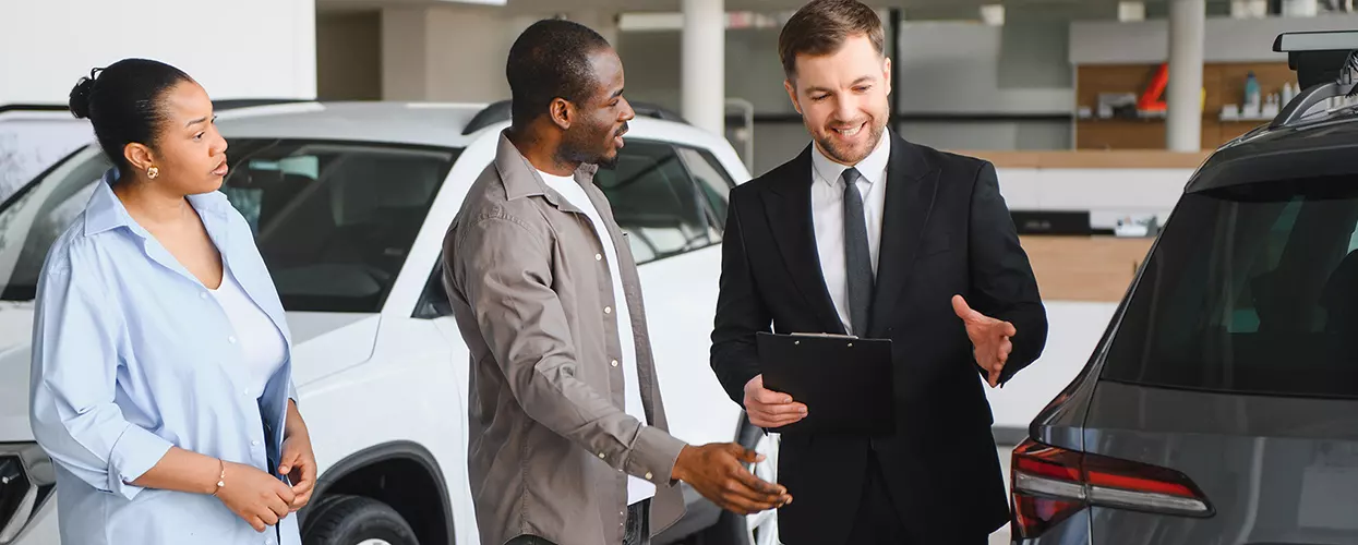 Car salesman showing a couple a new vehicle at a Genesis dealership