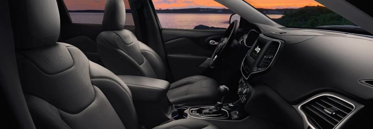 Side view of the front seats, steering wheel, and center console in the Jeep Cherokee.