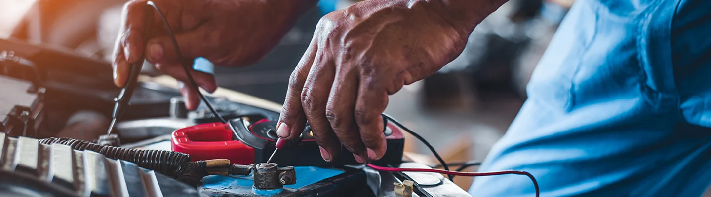 auto mechanic testing voltage on a bettery