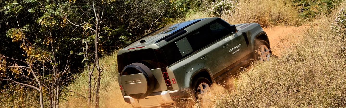 2025 Defender 130 driving up a hill in the wilderness