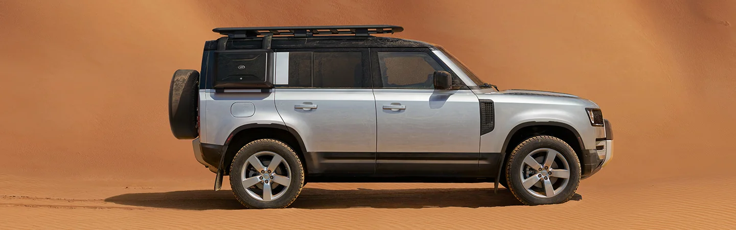 Side view of a parked 2025 Defender 130 in the sand