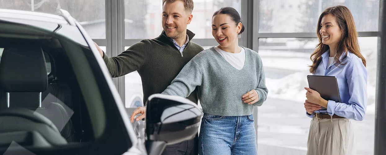 Car saleswoman showing a couple around a car dealership